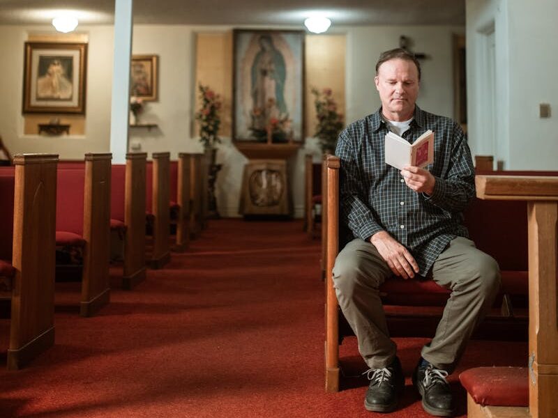 Man praying in a serene Catholic church interior, surrounded by religious icons.