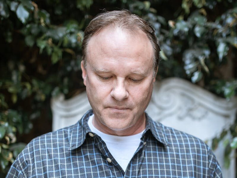 An adult man reads a Bible outdoors, exuding peace and contemplation in a serene setting.