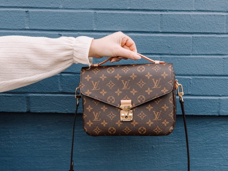 person holding brown leather sling bag