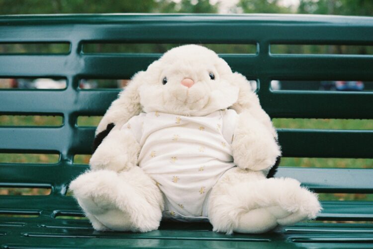a white stuffed rabbit sitting on top of a green bench