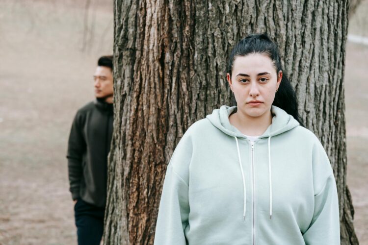Thoughtful young multiethnic people near big tree in autumn park gloomily looking forward