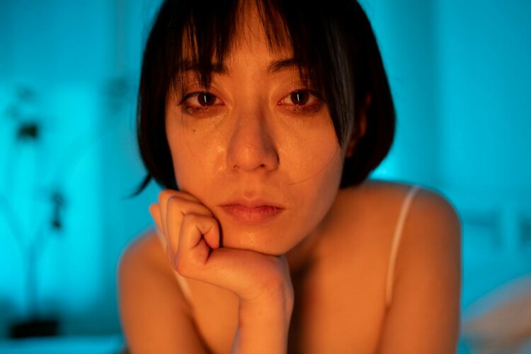 Close-up portrait of a woman with a contemplative expression in a softly lit room.
