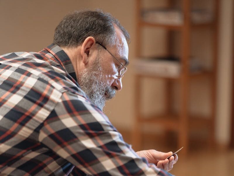 A senior adult man with eyeglasses playing a board game in a cozy home setting.