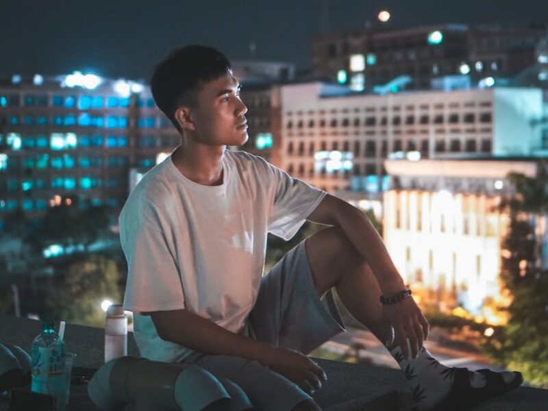 man in white crew neck t-shirt sitting on chair during night time