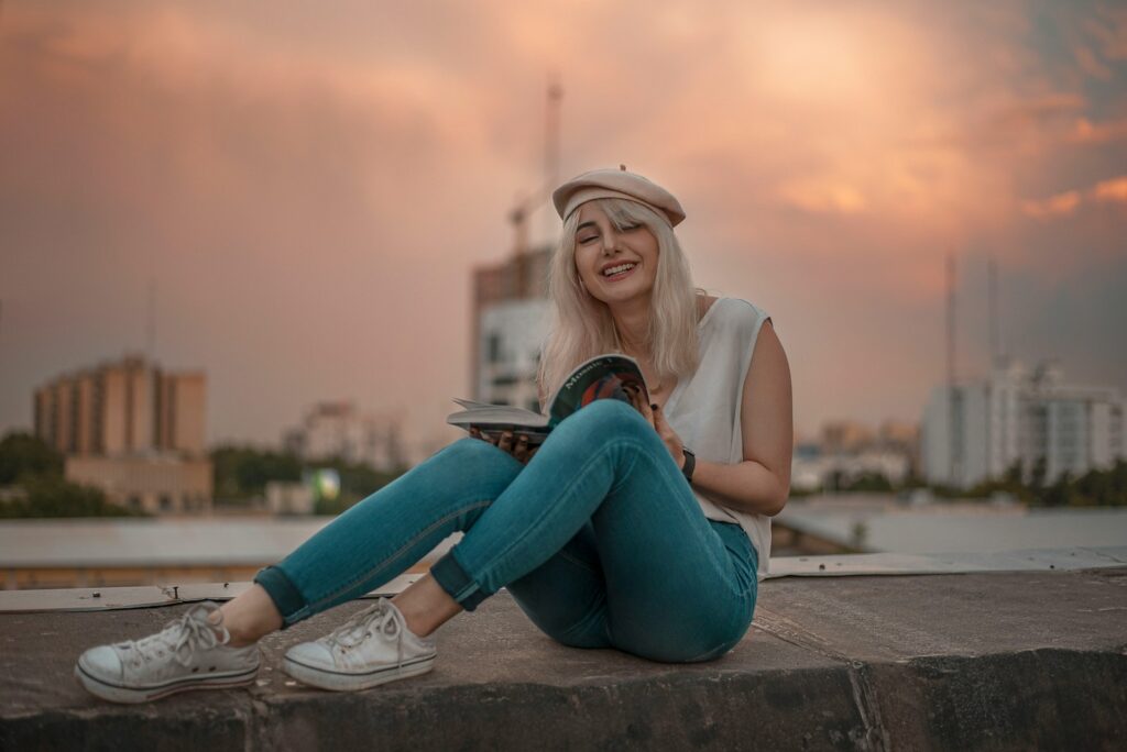a woman sitting on a ledge reading a book