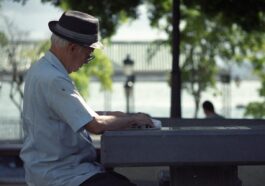 man in white dress shirt and black fedora hat sitting on bench