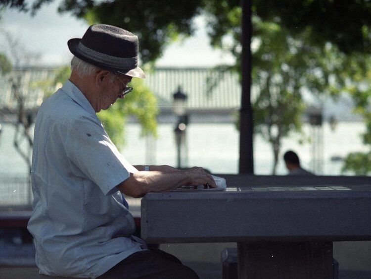 man in white dress shirt and black fedora hat sitting on bench