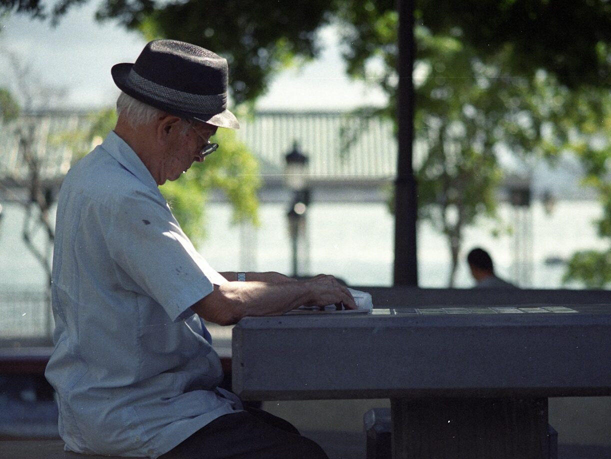 man in white dress shirt and black fedora hat sitting on bench
