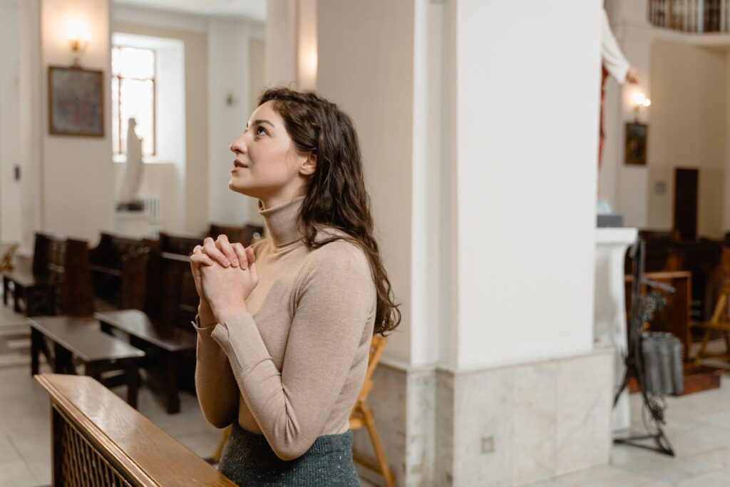 A woman deeply engaged in prayer inside a serene church setting, highlighting faith and spirituality.