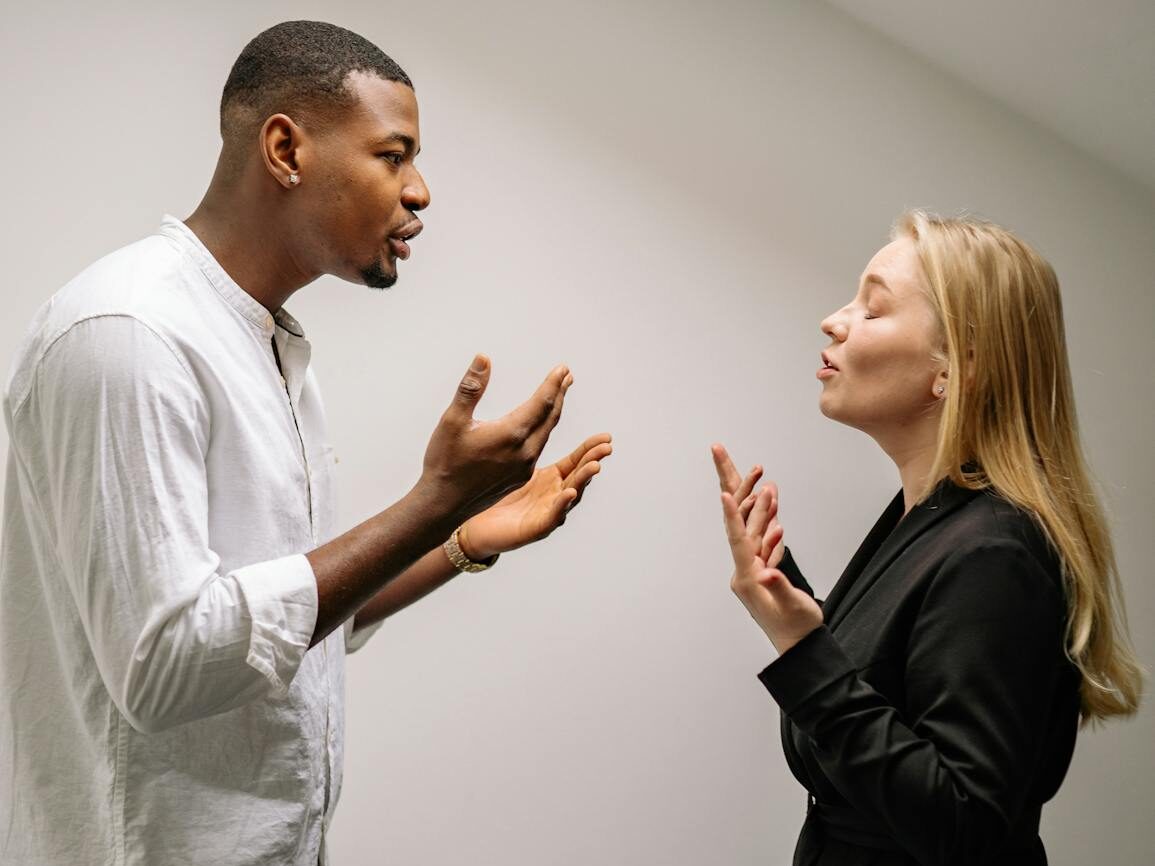 A couple engaged in a heated argument indoors, expressing strong emotions and gestures.