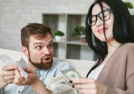 Interracial couple arguing over bills and cash at home.