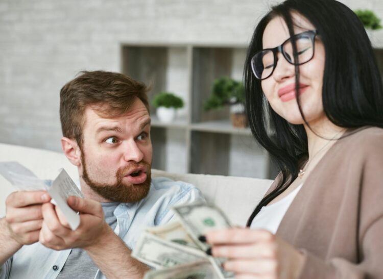 Interracial couple arguing over bills and cash at home.