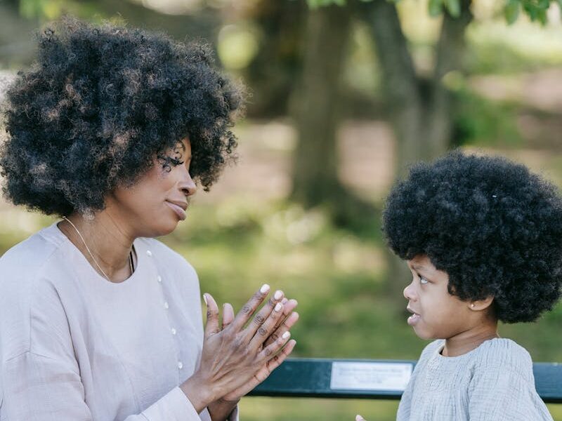 Woman and child seated outdoors, engaging in prayer or storytelling, promoting bonding.