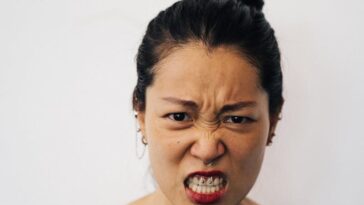 Portrait of an Asian woman expressing anger with fierce facial expression against a clean white background.