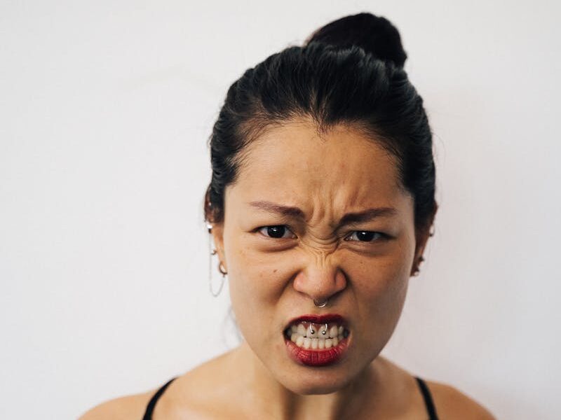 Portrait of an Asian woman expressing anger with fierce facial expression against a clean white background.