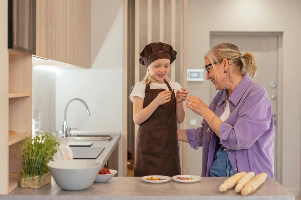 A joyful moment of a grandmother and granddaughter baking sweets in a modern kitchen.