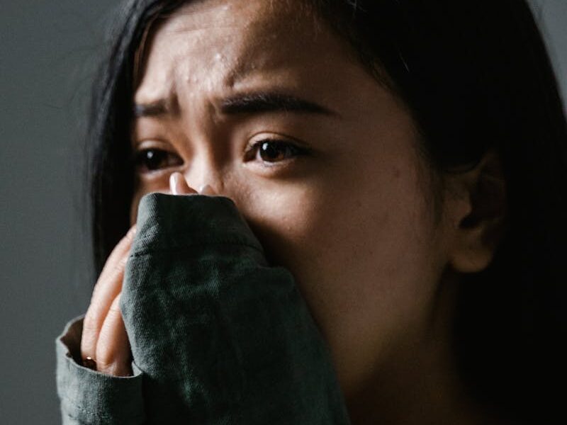 Close-up of a distressed woman indoors, showing anxiety and stress.