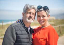 A joyful senior couple smiling together at a sunny beach in Portugal.