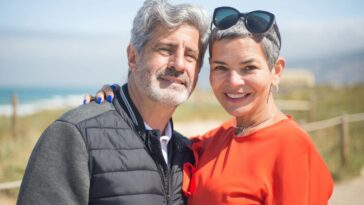 A joyful senior couple smiling together at a sunny beach in Portugal.