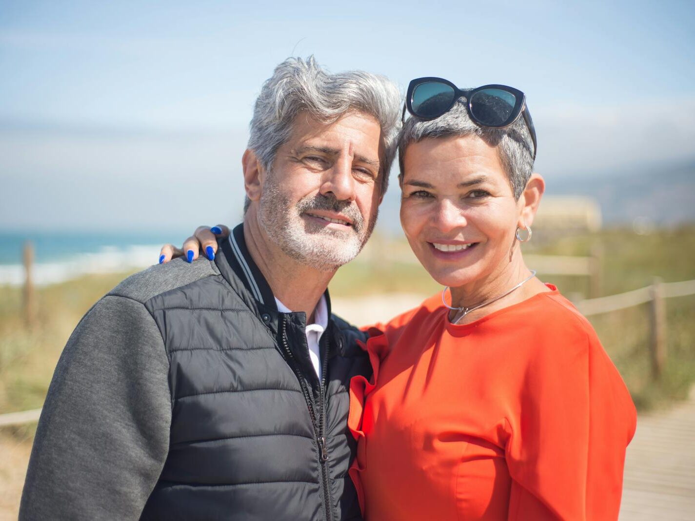 A joyful senior couple smiling together at a sunny beach in Portugal.