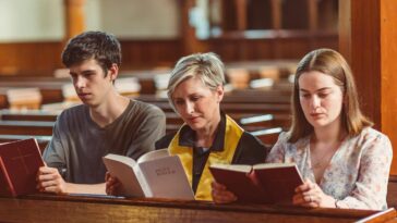 Three individuals reading bibles together in a church setting.