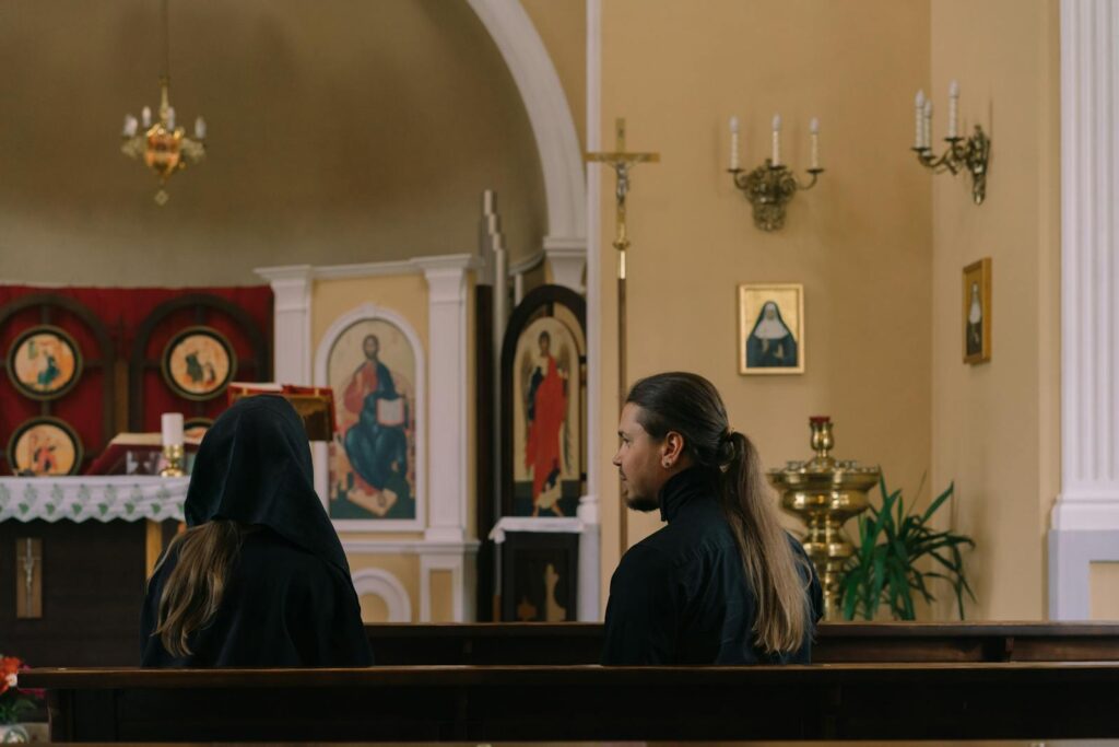 Two people sitting in church pews, showcasing a moment of religious reflection and spirituality.