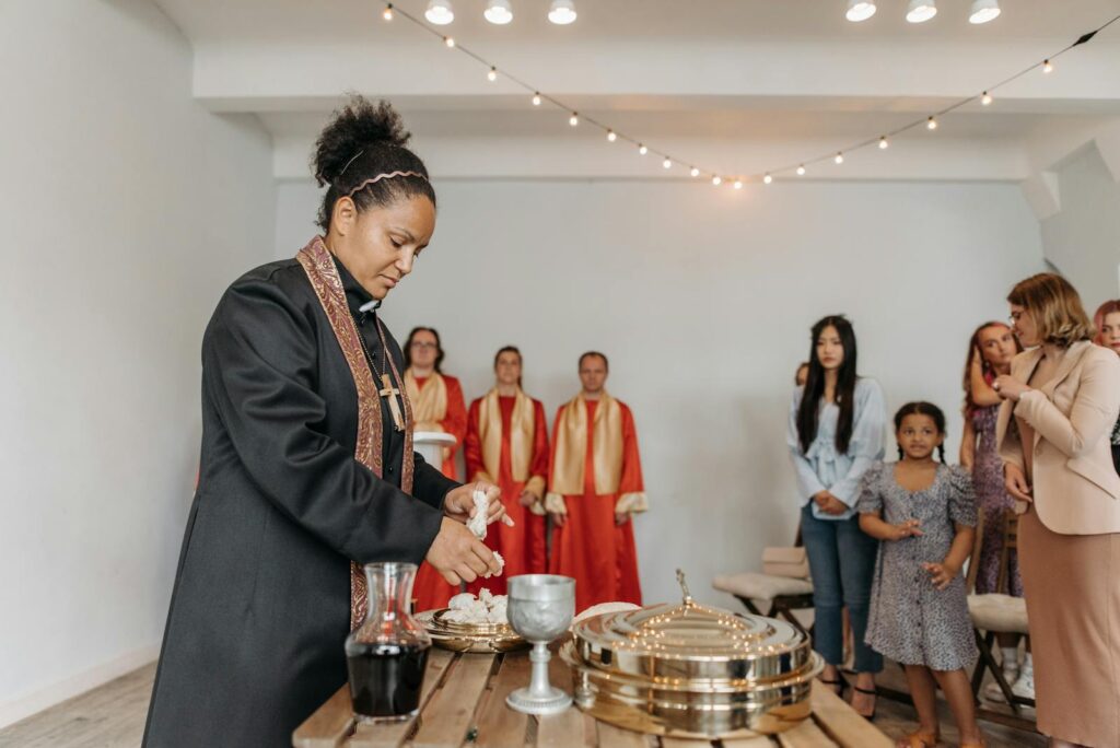 A diverse group of people attending a religious ceremony with a priest performing rituals indoors.