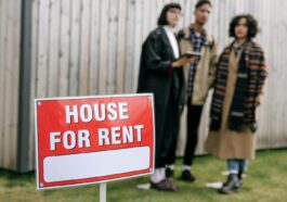 Three adults examining a house for rent sign outdoors, depicting diverse and inclusive interest in rental properties.
