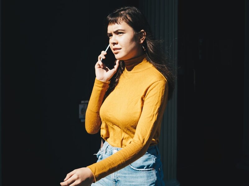 woman walking with phone on her right ear during daytime