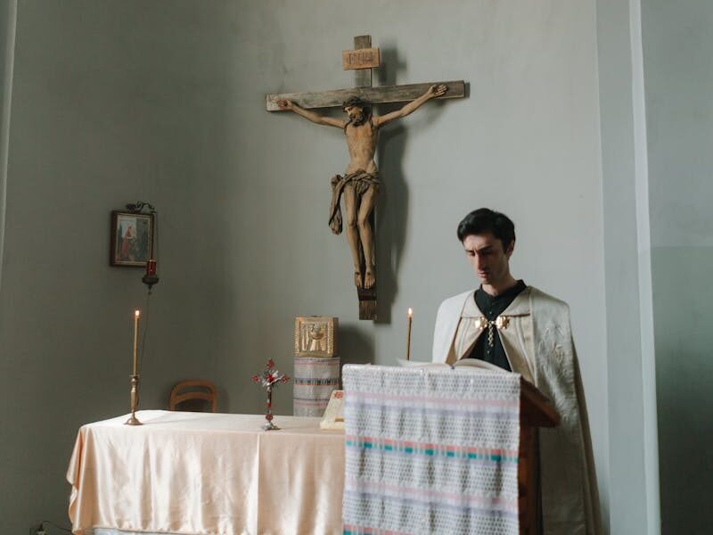 A priest performs a religious service at a podium with a crucifix in a church.