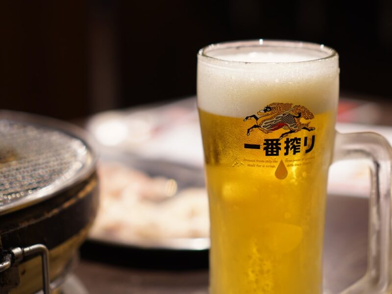 a glass of beer sitting on top of a wooden table