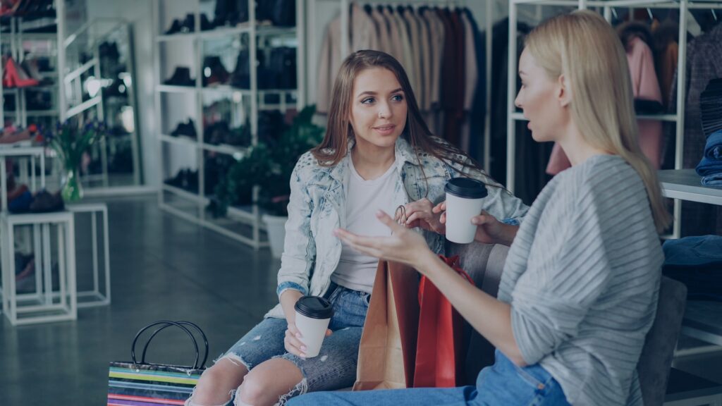 Two women chat while resting in a boutique.