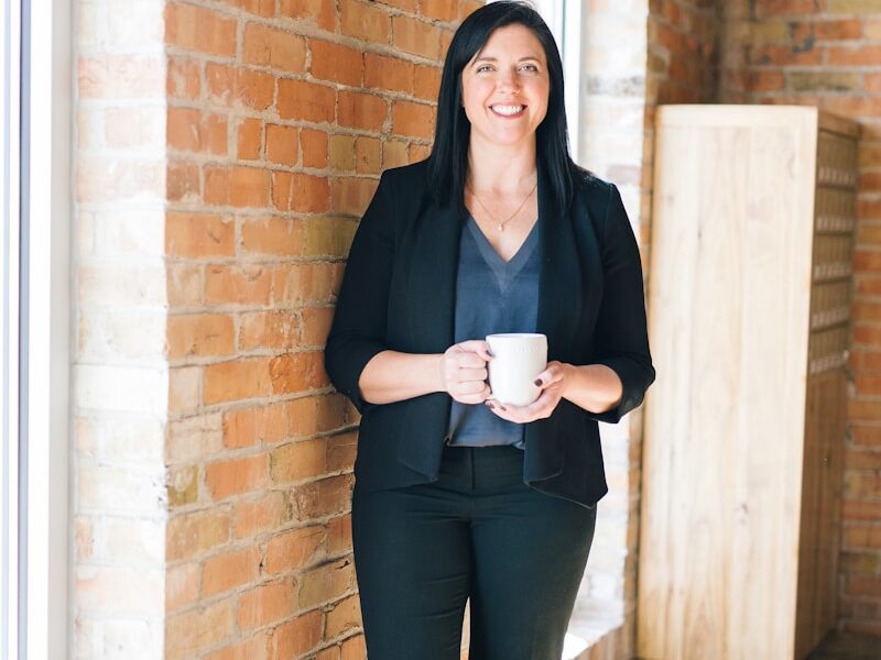 woman standing by wall holding mug