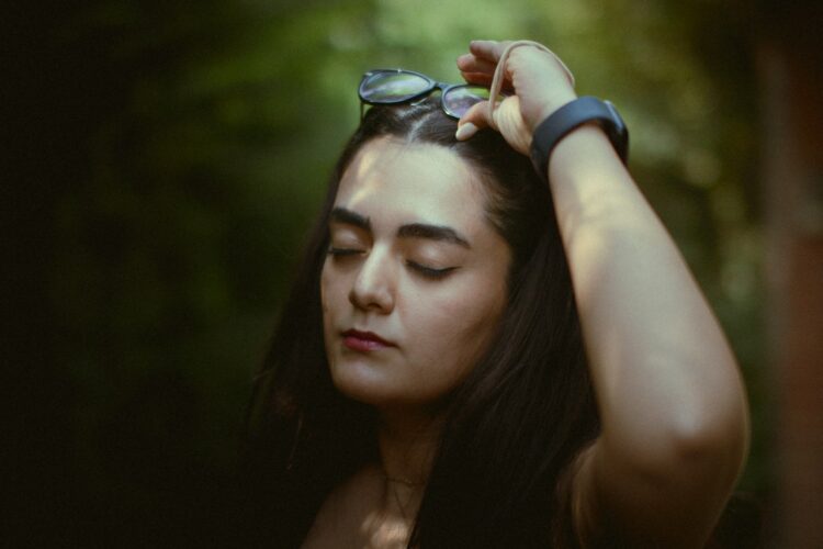 Woman touching her hair with eyes closed.