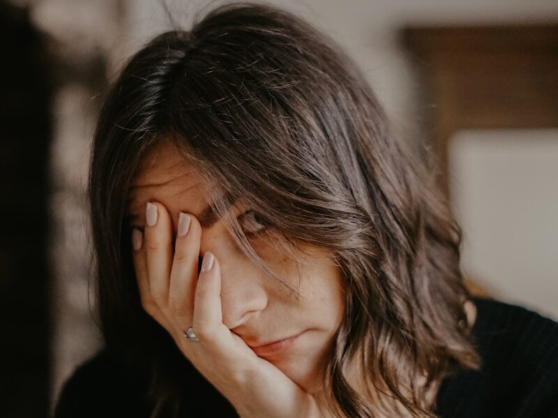 woman in black blazer covering her face