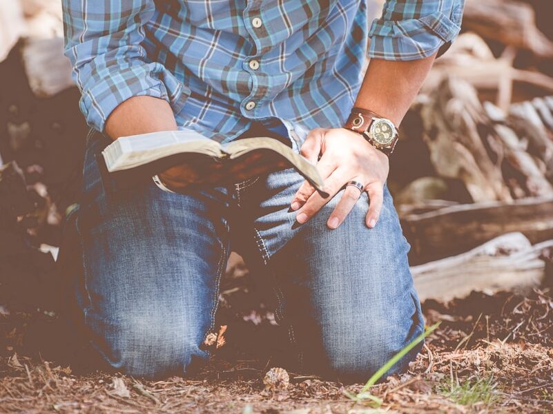 person reading book while kneeling