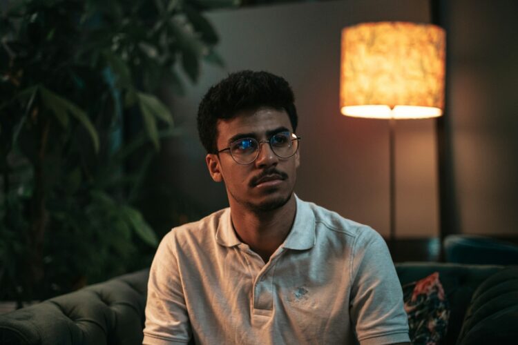 a man wearing glasses sitting on a couch