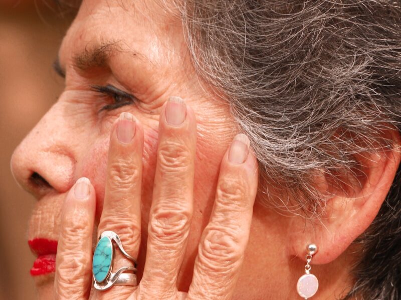 an older woman holding her hands to her face