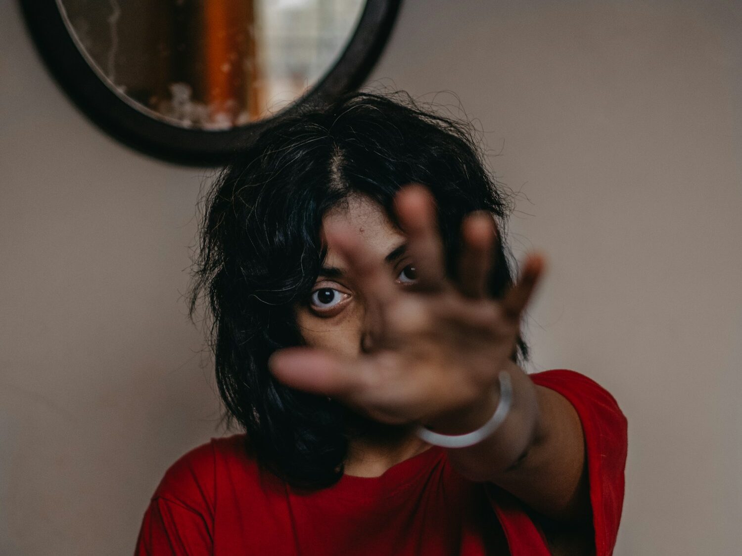 a woman making a hand gesture in front of a mirror