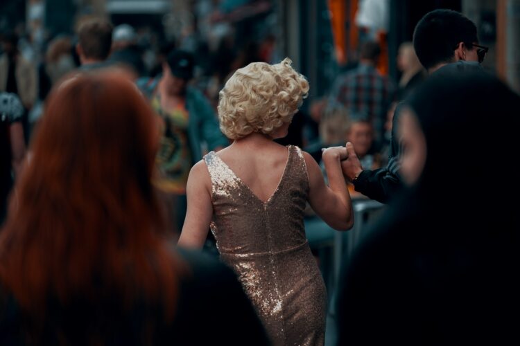 a woman in a gold dress walking down a street