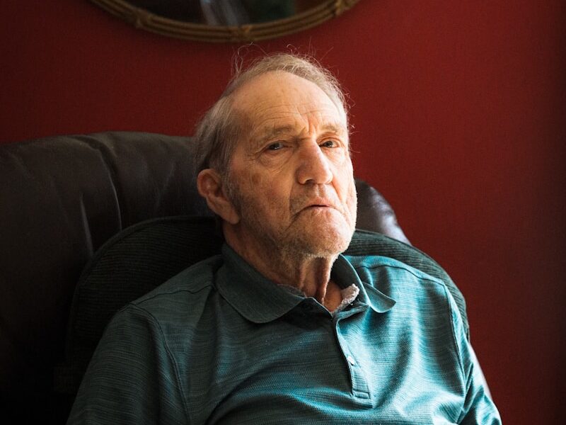 man in blue sweater sitting on black sofa