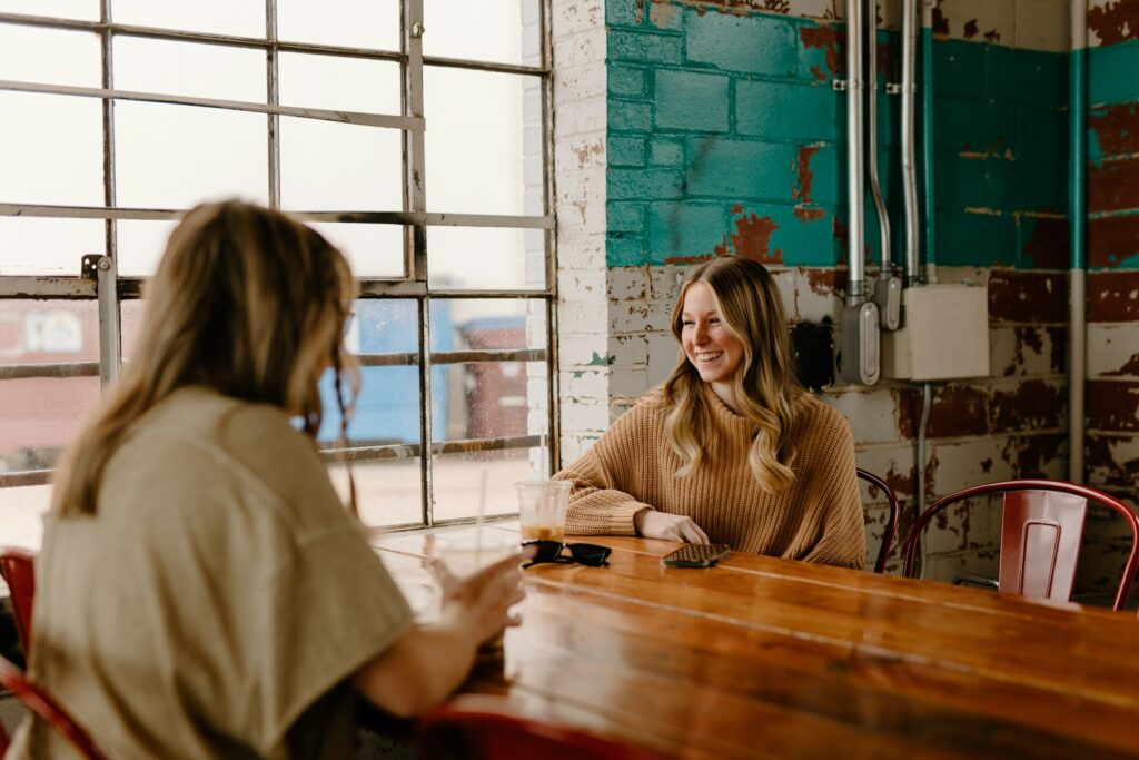 a woman sitting at a table talking to another woman