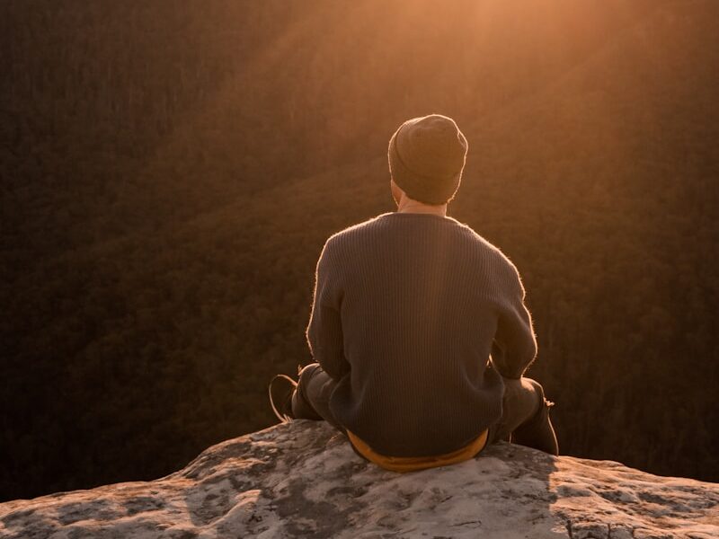 man in bonnet sitting on top of mountain