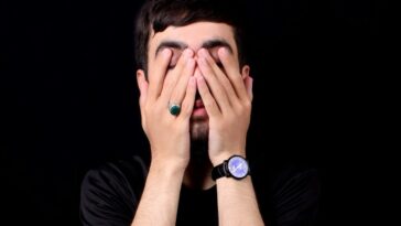 a man holding his hands to his face