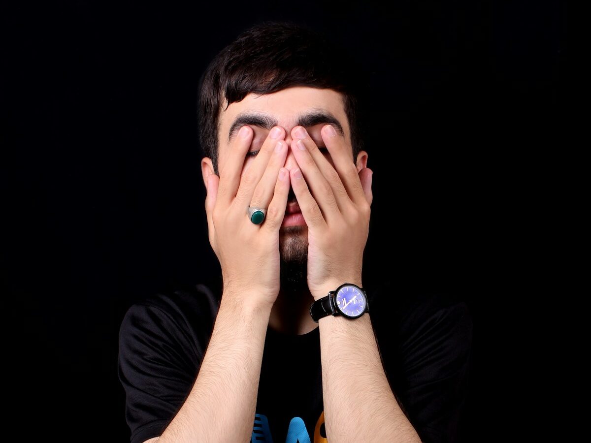 a man holding his hands to his face