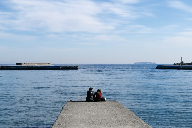 a couple of people sitting on top of a pier