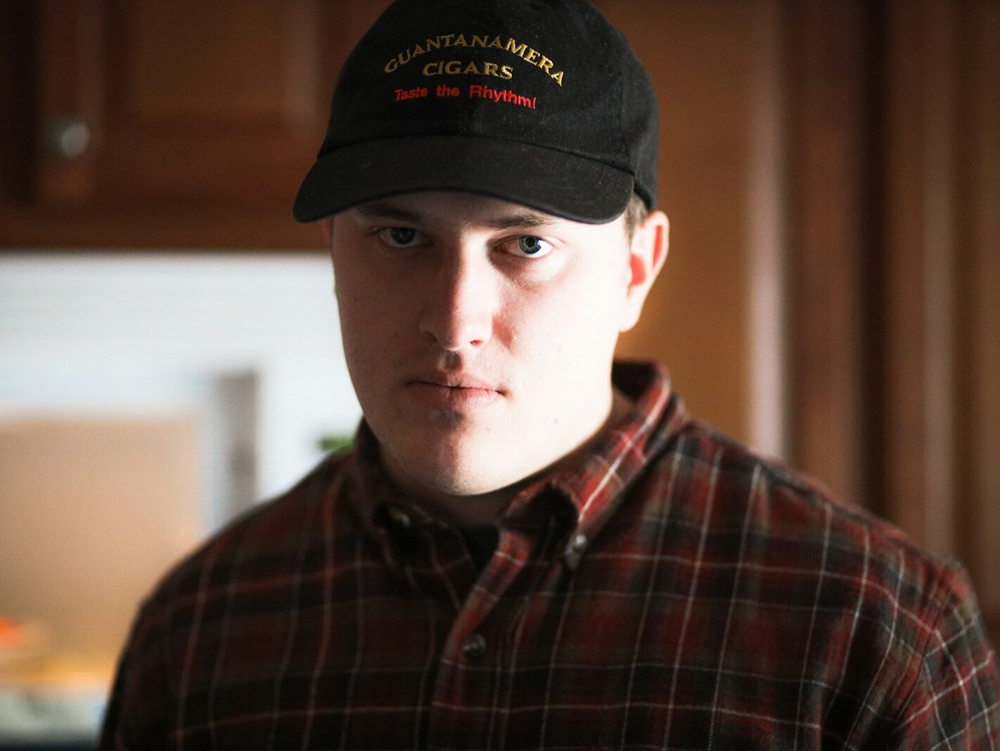 man in black and red plaid button up shirt wearing black cap