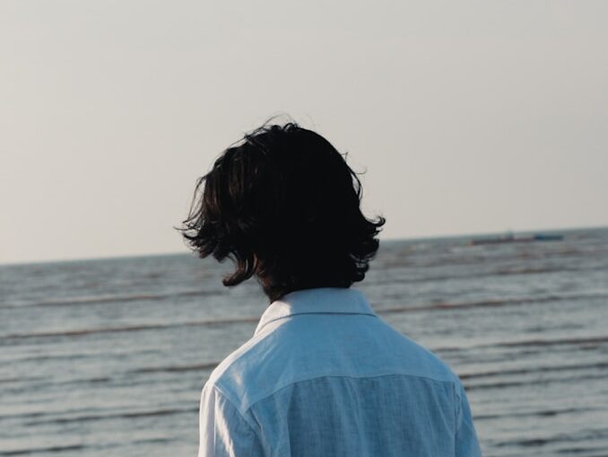 A man standing on a beach next to the ocean