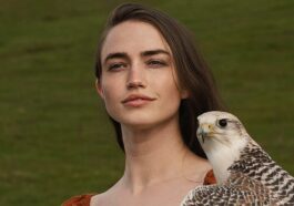 a woman holding a bird of prey in her hand