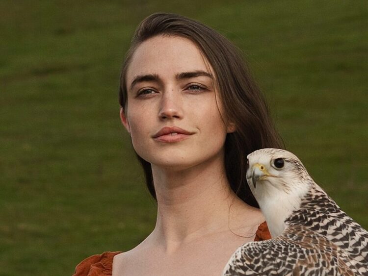 a woman holding a bird of prey in her hand